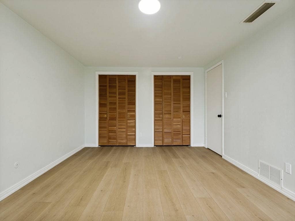 2018 Vail Drive, Garland, TX 75044 Light wood-finish flooring, two sets of louvered bifold closet doors, and white walls