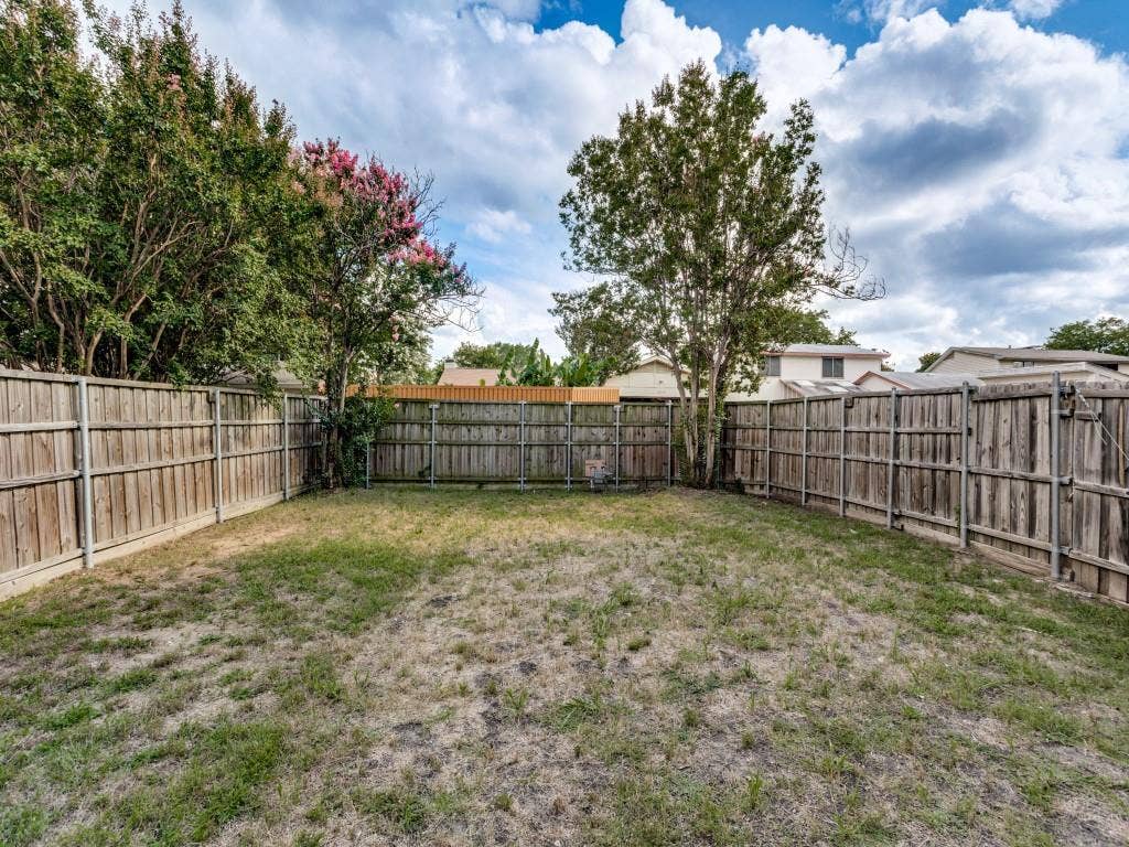 2018 Vail Drive, Garland, TX 75044 Enclosed backyard featuring wood fencing, mature trees, and a grass lawn