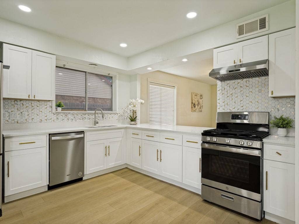 2018 Vail Drive, Garland, TX 75044 Kitchen featuring white cabinetry, stainless steel appliances, quartz countertops, a patterned tile backsplash, and wood-finish flooring
