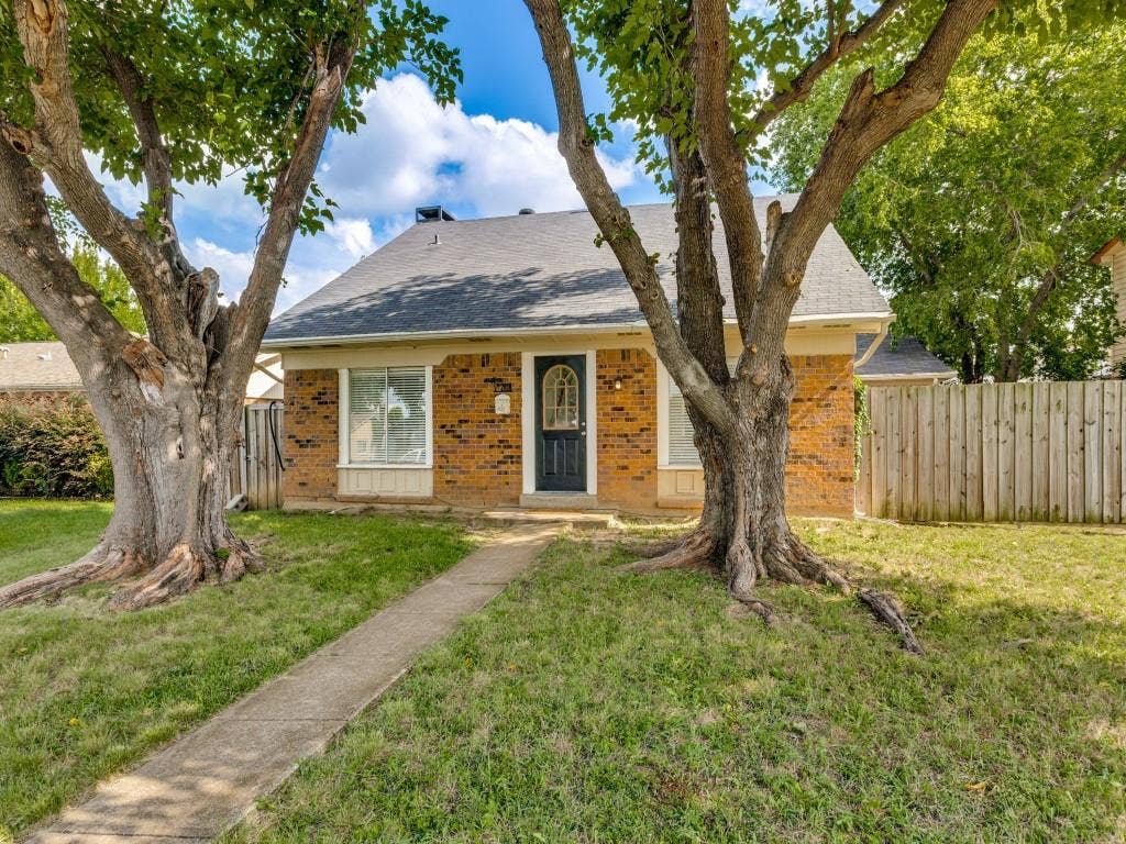 2018 Vail Drive, Garland, TX 75044 Red brick exterior with a black front door, a light gray roof, and prominent mature trees