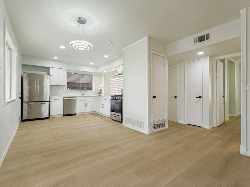 2018 Vail Drive, Garland, TX 75044 Open-concept kitchen featuring white cabinetry, stainless steel appliances, and a mosaic tile backsplash