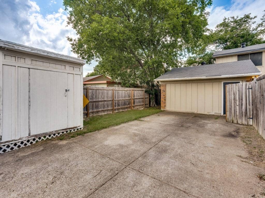 2018 Vail Drive, Garland, TX 75044 Detached storage shed, wood privacy fencing, concrete driveway, attached garage, and mature trees