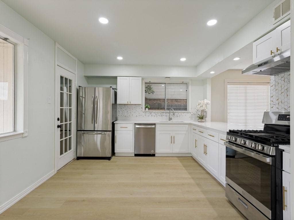 2018 Vail Drive, Garland, TX 75044 White cabinetry with gold-tone hardware, stainless steel appliances, wood-finish flooring, and recessed ceiling lighting