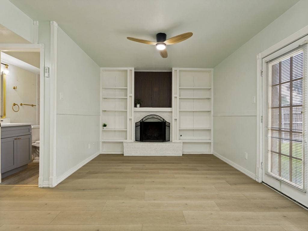 2018 Vail Drive, Garland, TX 75044 Wood-finish flooring, built-in shelving, a fireplace with a decorative screen, a ceiling fan with integrated lighting, and a glass-paned door