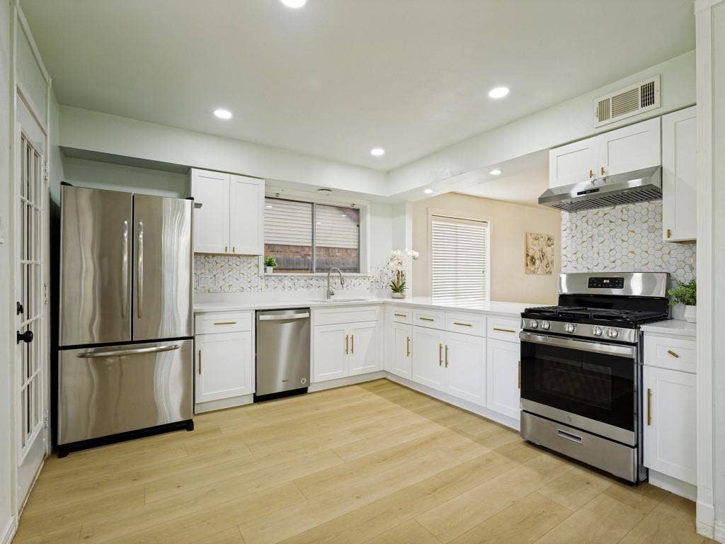2018 Vail Drive, Garland, TX 75044 Full kitchen with white cabinetry, stainless steel appliances, patterned tile backsplash, light-toned wood-finish flooring, and recessed lighting