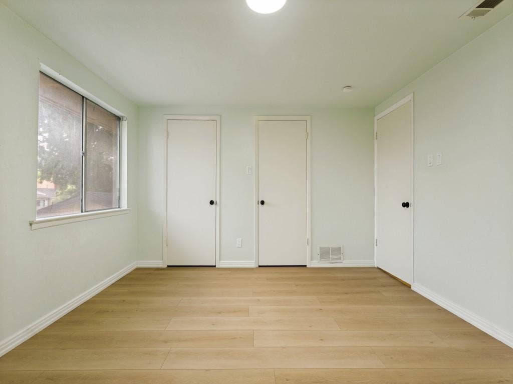 2018 Vail Drive, Garland, TX 75044 Wood-finish flooring, multiple white doors, and a window with a white frame