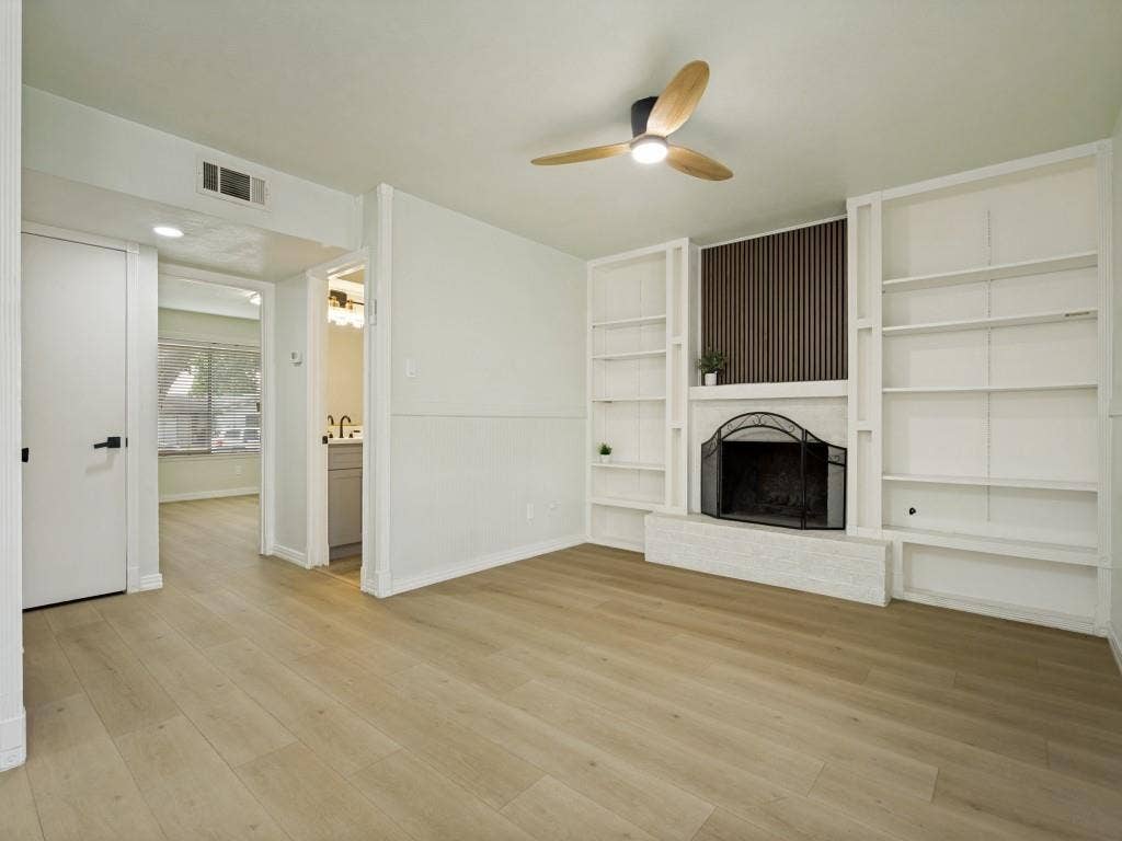 2018 Vail Drive, Garland, TX 75044 Wood-finish flooring throughout, fireplace with a decorative screen, built-in shelving, and a ceiling fan with integrated lighting