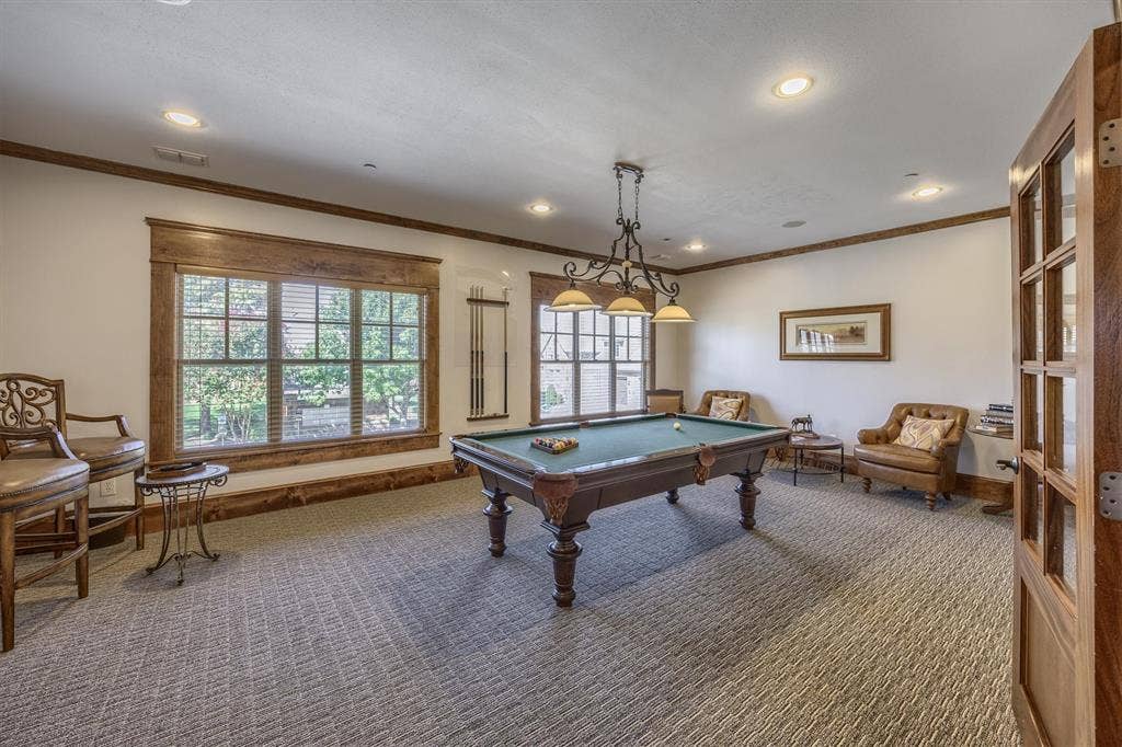 Recessed lighting, wood-trimmed windows, patterned carpeting, wood-frame door, and a multi-light chandelier