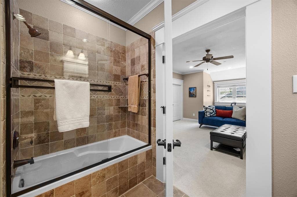 Beautiful glass sliding shower doors and tumbled tile surround with access into the guest quarters or 3rd bedroom of the home.
