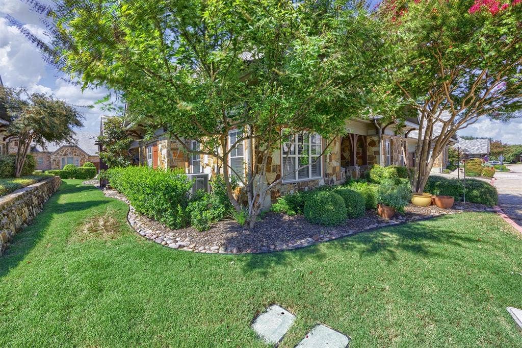 Stunning landscaping with perfectly pruned flower beds and lush grassy area.