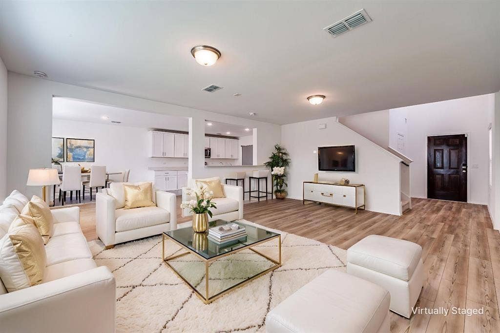 845 Poppy Cove Lane, Princeton, TX 75407 Wood-finish flooring throughout the main living areas, a staircase with a white railing, and a dark-paneled entry door