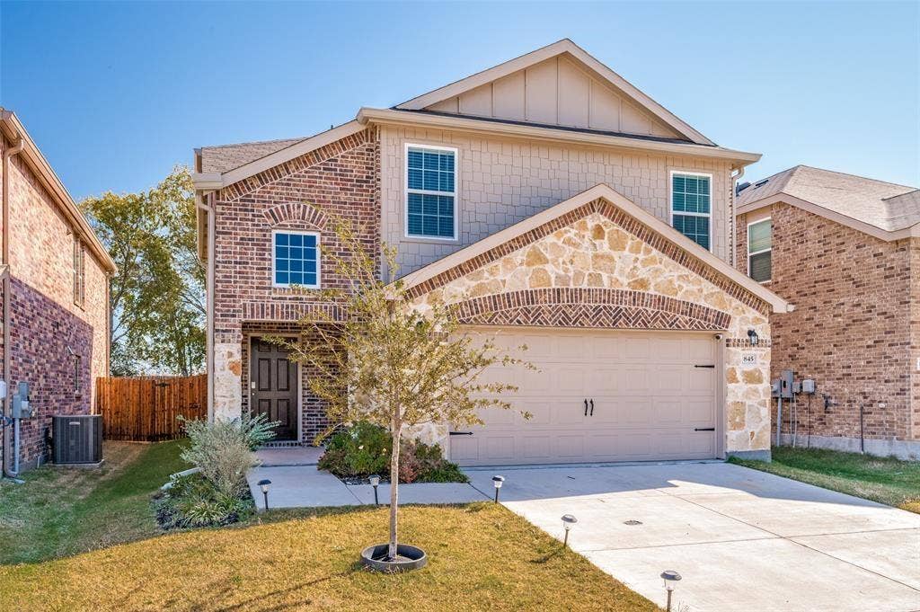 845 Poppy Cove Lane, Princeton, TX 75407 Brick and stone facade with a gable roofline, attached two-car garage, covered entry, and front landscaping