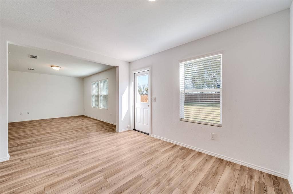 845 Poppy Cove Lane, Princeton, TX 75407 Open-concept living space featuring wood-finish flooring, white walls, and a prominent window with blinds