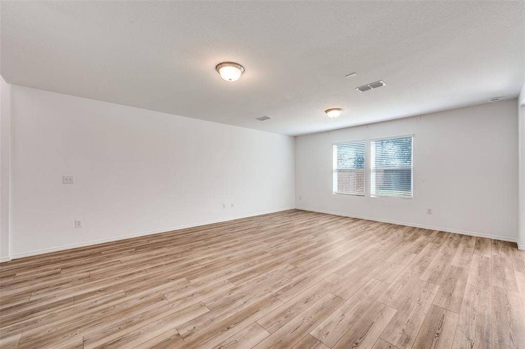 845 Poppy Cove Lane, Princeton, TX 75407 Expansive room featuring wood-finish flooring, white walls, multiple windows with blinds, and flush-mount ceiling lighting