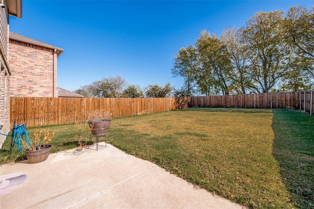 845 Poppy Cove Lane, Princeton, TX 75407 Expansive backyard with a concrete patio, wood privacy fence, and mature trees