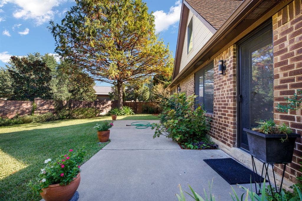 765 Eiffel Drive, Plano, TX 75023 Brick exterior with a gabled roofline, concrete patio, and mature landscaping