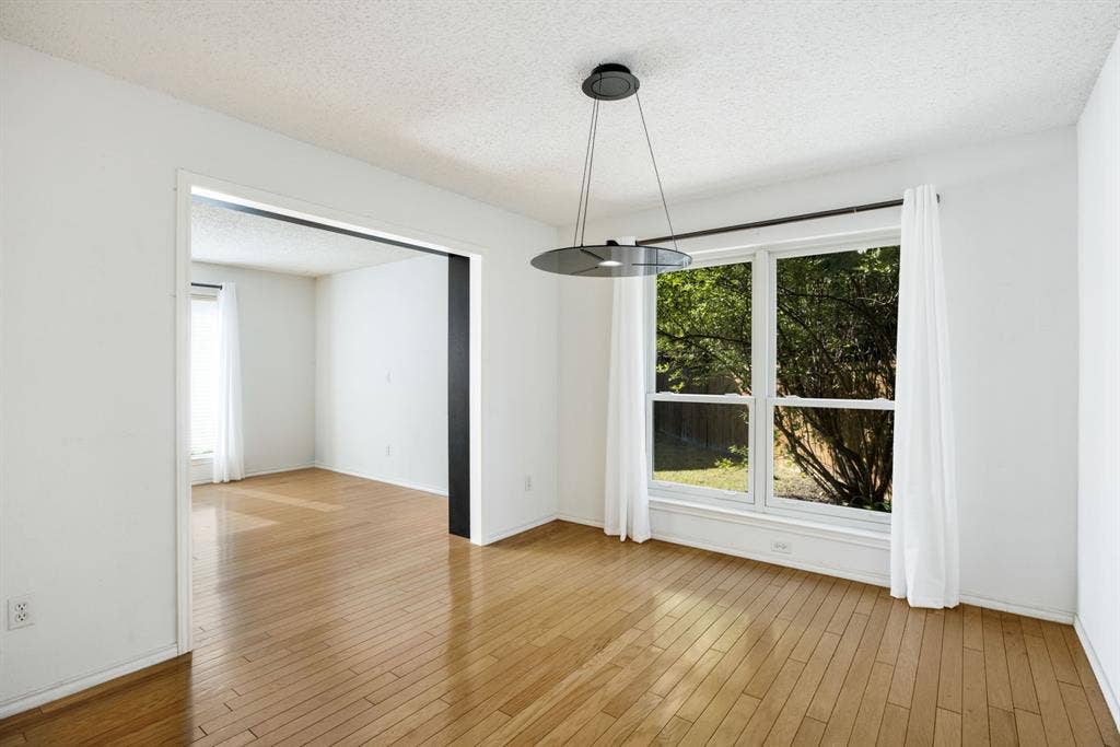 765 Eiffel Drive, Plano, TX 75023 Wood-finish flooring, white walls, modern pendant light fixture, and large window with white casing
