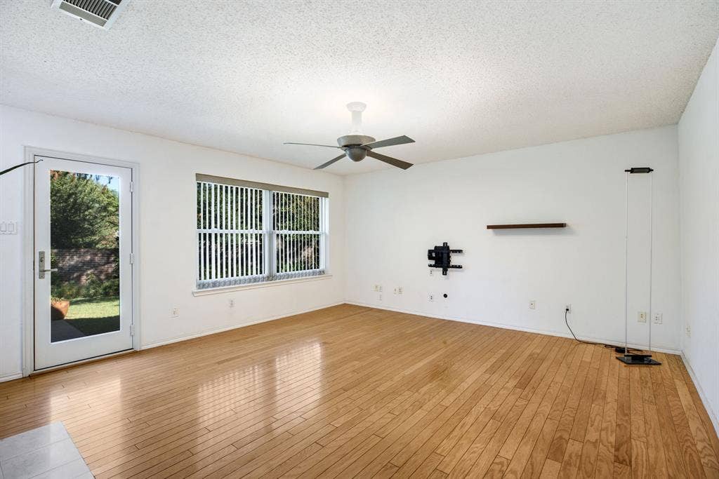 765 Eiffel Drive, Plano, TX 75023 Wood-finish flooring throughout, ceiling fan, large window with vertical blinds, and a glass-paneled door