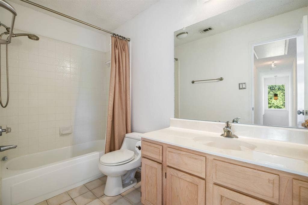 765 Eiffel Drive, Plano, TX 75023 White tile flooring, single vanity with wood-finish cabinetry, integrated sink, and an expansive wall-mounted mirror