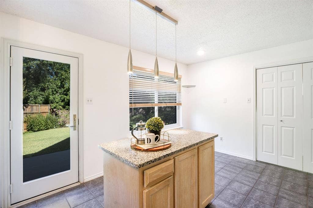 765 Eiffel Drive, Plano, TX 75023 Kitchen island with a granite-style countertop, pendant lighting, and wood-finish cabinetry
