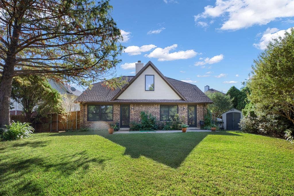 765 Eiffel Drive, Plano, TX 75023 Brick exterior with an A-frame architectural element, featuring a shingled roof, a prominent chimney, and a landscaped yard with mature trees