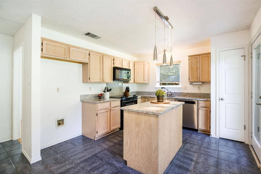 765 Eiffel Drive, Plano, TX 75023 Kitchen featuring an island, light wood-finish cabinetry, granite countertops, tile flooring, and a stainless steel dishwasher