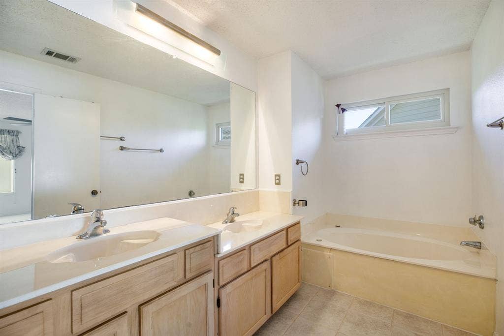765 Eiffel Drive, Plano, TX 75023 Dual vanity with integrated sinks, light wood-finish cabinetry, and a large wall-mounted mirror