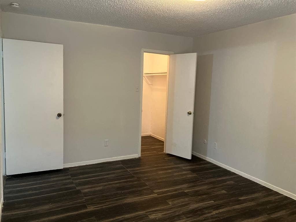 5727 Harvest Hill Road, #1042, Dallas, TX 75230 Gray walls with white trim, dark wood-finish flooring, and white interior doors