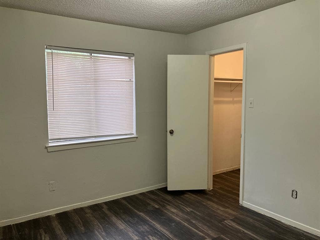 5727 Harvest Hill Road, #1042, Dallas, TX 75230 Room featuring wood-finish flooring, a window with blinds, and a built-in closet with shelving