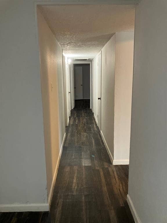 5727 Harvest Hill Road, #1042, Dallas, TX 75230 Hallway featuring wood-finish flooring and bright overhead lighting throughout, with multiple doorways providing access to adjoining spaces