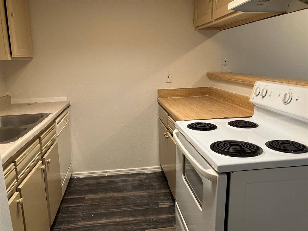 5727 Harvest Hill Road, #1042, Dallas, TX 75230 Wood-finish flooring, white electric range, wood-finish countertops, stainless steel double-basin sink, and overhead cabinetry