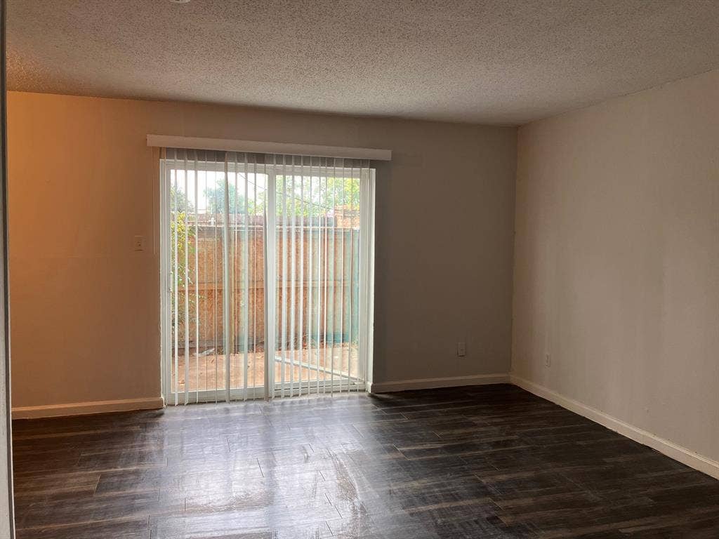 5727 Harvest Hill Road, #1042, Dallas, TX 75230 Sliding glass door with vertical blinds, wood-finish flooring, and neutral wall paint