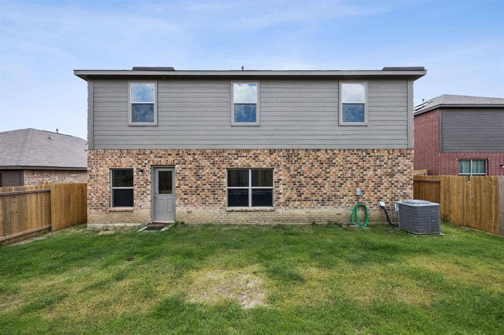 Exterior featuring brick and siding finishes, multiple windows, and a private fenced yard