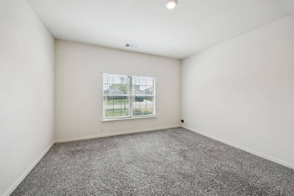 Neutral wall paint, gray carpeting, window with horizontal blinds, recessed ceiling light, and ceiling air vent