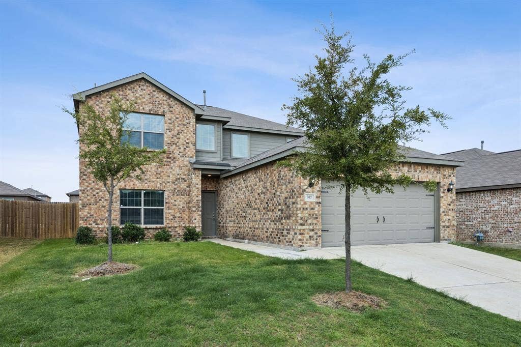 Brick and siding exterior with a two-car garage, concrete driveway, and front yard landscaping