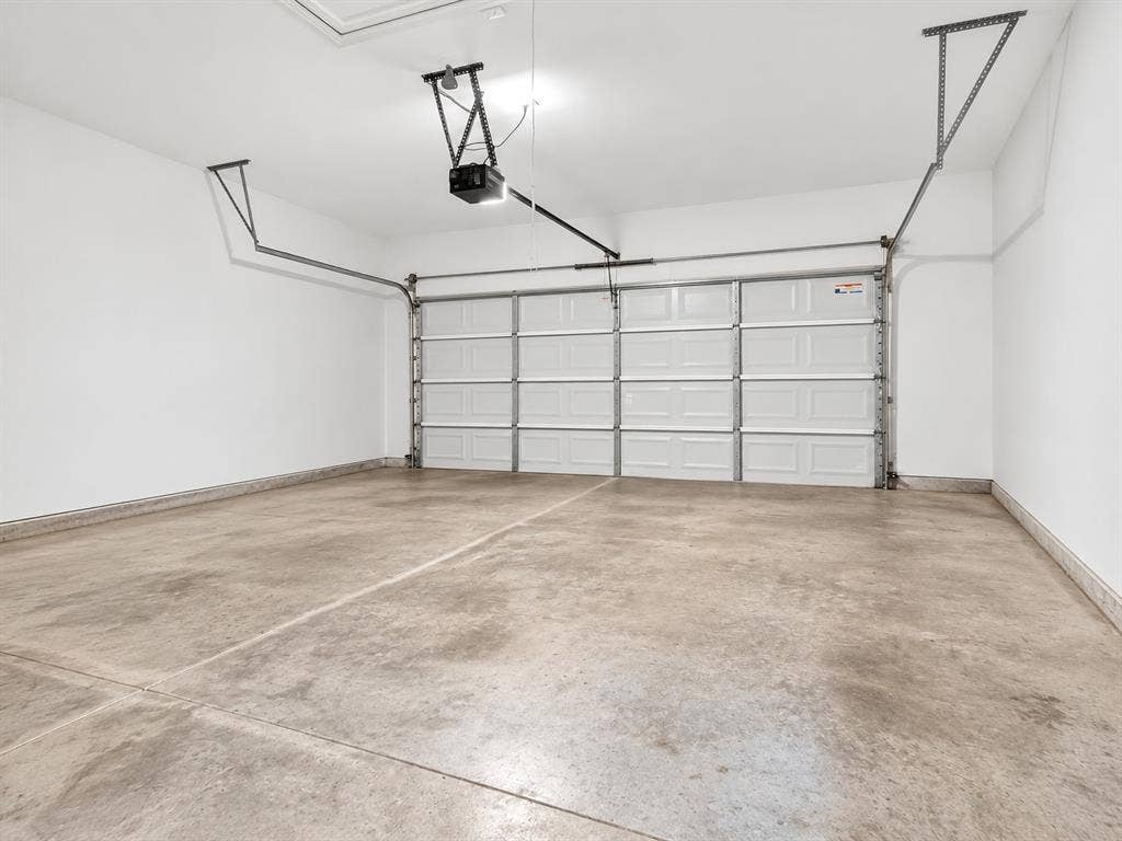 Concrete flooring with a segmented overhead garage door, equipped with an automatic opener
