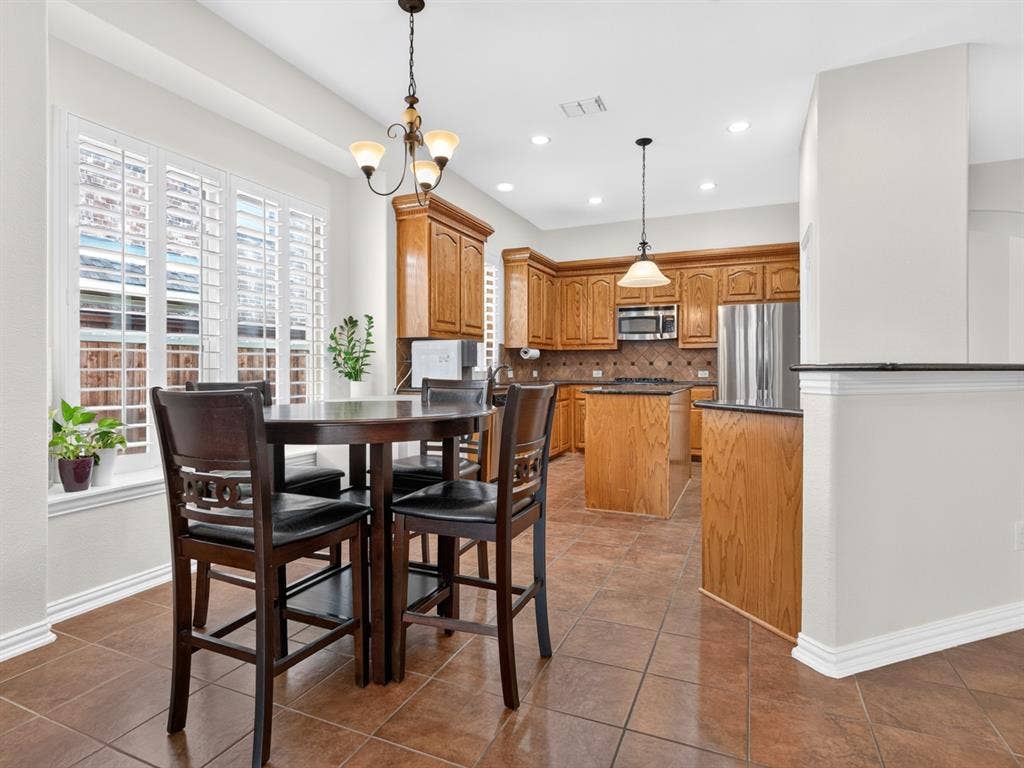 Kitchen with wood cabinetry, stainless steel appliances, and a tiled backsplash