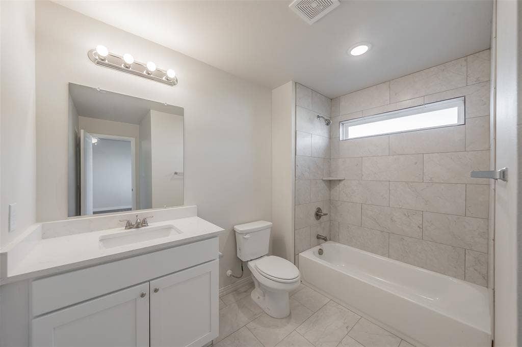 6215 Roby Drive, Arlington, TX 76001 Full bathroom with tiled shower / bath combo, vanity, and toilet