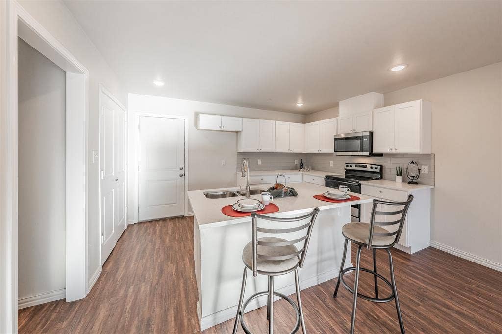 6215 Roby Drive, Arlington, TX 76001 Kitchen with white Shaker cabinets, stainless steel appliances, sink, and luxury vinyl dark hardwood / wood-style flooring