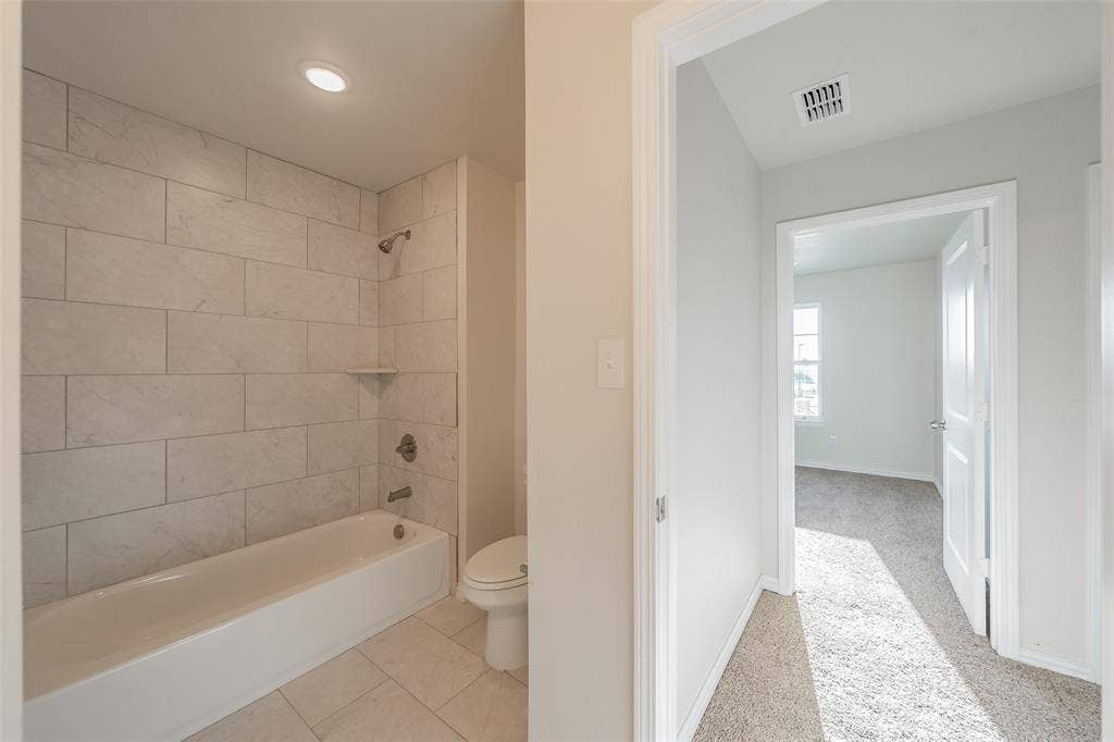 6215 Roby Drive, Arlington, TX 76001 Hallway Bathroom with tiled shower / bath combo, tile patterned flooring, and toilet
