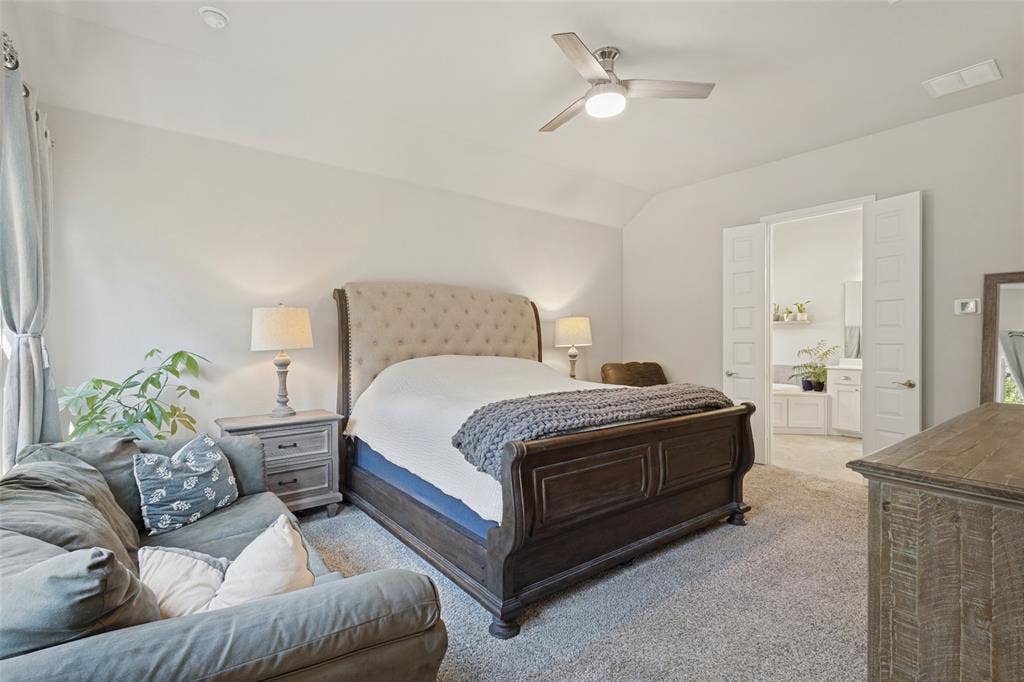 Vaulted ceiling, ceiling fan, neutral wall paint, carpet flooring, and double doors