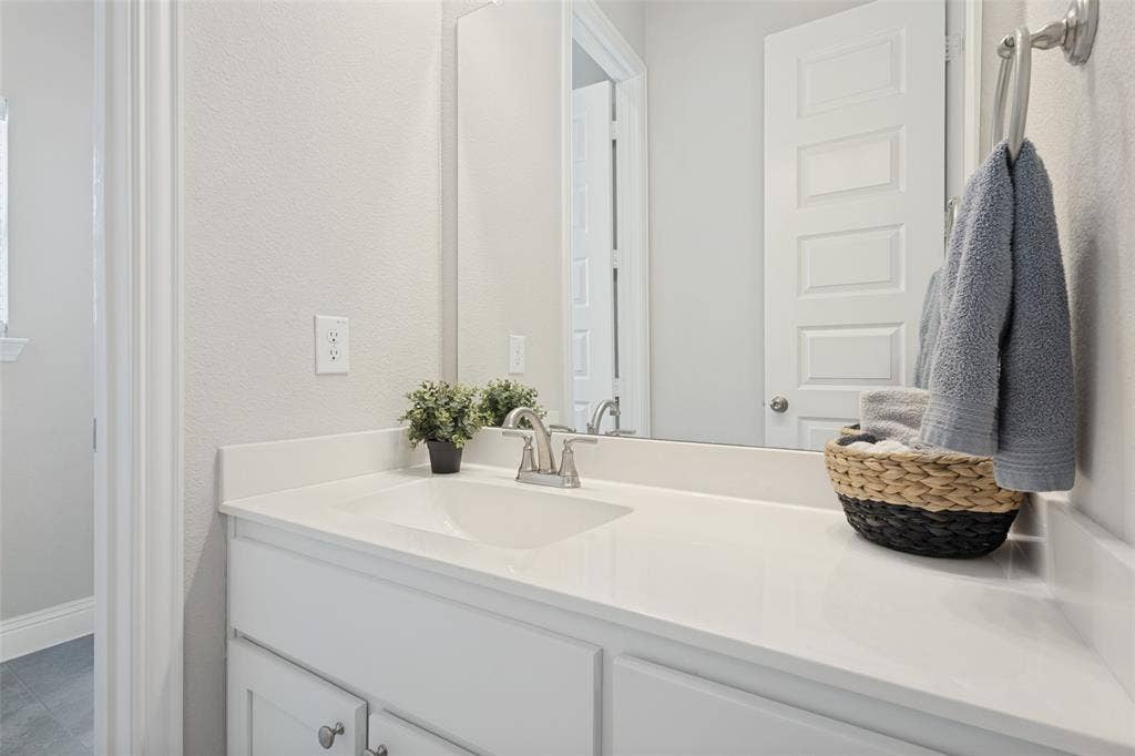 White vanity with a built-in sink, polished chrome faucet, and expansive countertop