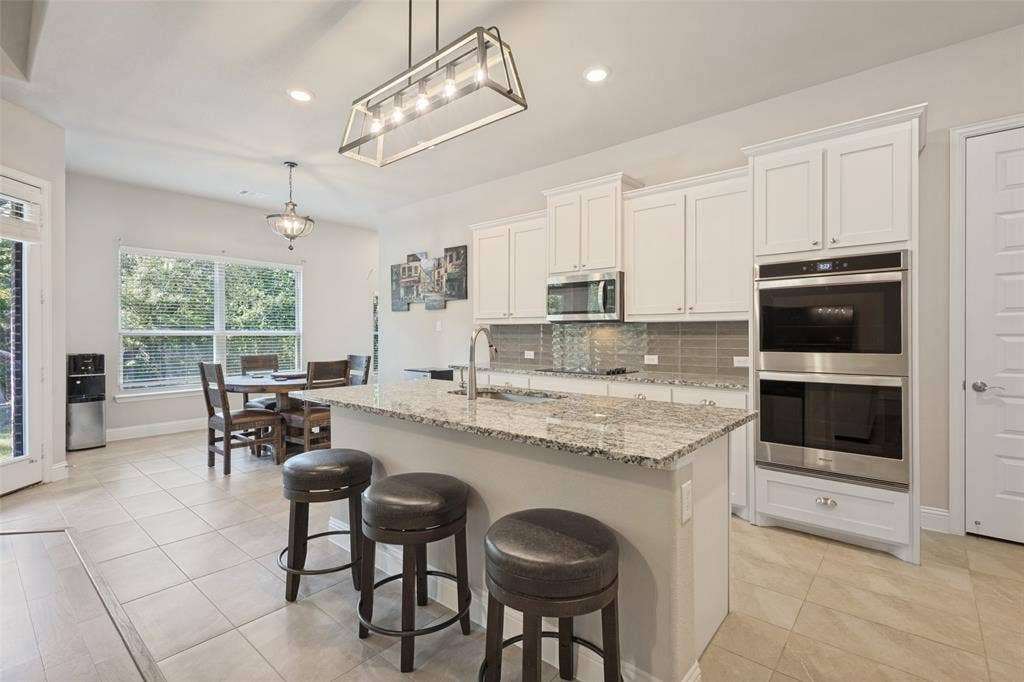 Kitchen featuring a central island with countertop, white cabinetry, stainless steel appliances, and tile flooring