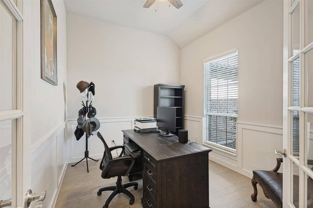 Vaulted ceiling, paneled accent walls, French doors, ceiling fan, and wood-finish flooring