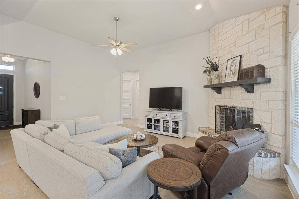 Vaulted ceilings with recessed lighting, stone-clad fireplace, wood-finish flooring, and a ceiling fan