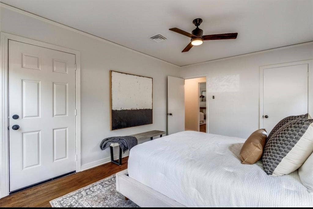 Wood-finish flooring, white paneled doors, ceiling fan with integrated lighting, and neutral wall tones