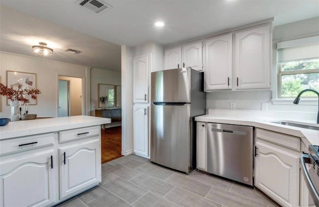 White cabinetry with black hardware, stainless steel appliances, quartz countertops, tile flooring, and recessed lighting