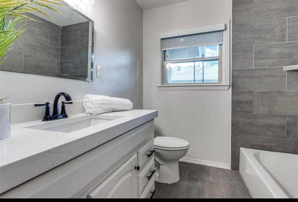 White vanity with a rectangular undermount sink, quartz countertop, and matte black faucet