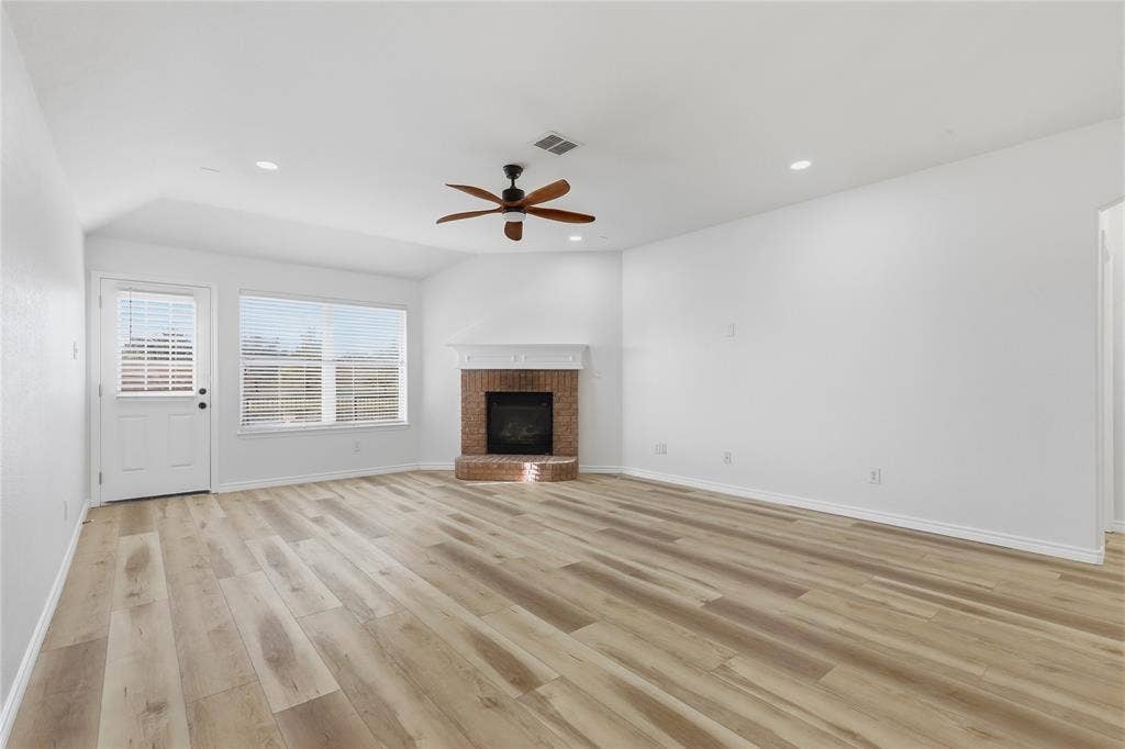 10709 Nantucket Drive, Rowlett, TX 75089 Spacious living area featuring wood-finish flooring, a brick fireplace, and a ceiling fan