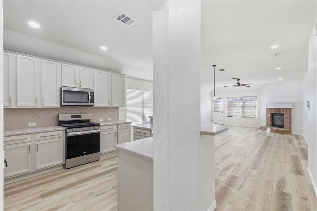 10709 Nantucket Drive, Rowlett, TX 75089 Kitchen featuring white cabinetry, stainless steel appliances, and a tiled backsplash